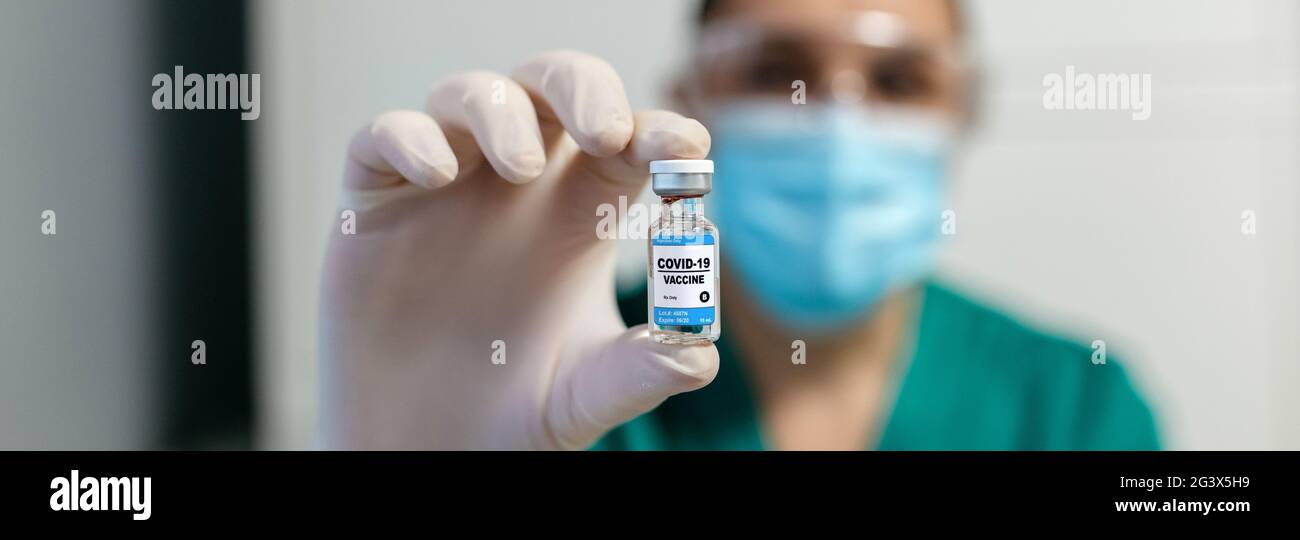 Female laboratory technician showing vial of coronavirus vaccine Stock Photo