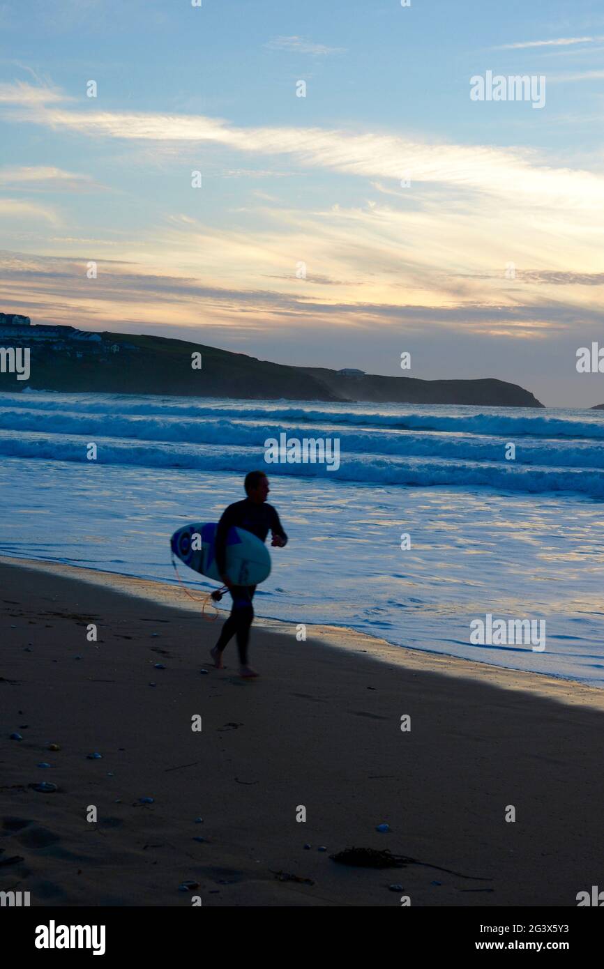 Surfer at sunset on Fistral Beach, Newquay, Cornwall, UK Stock Photo