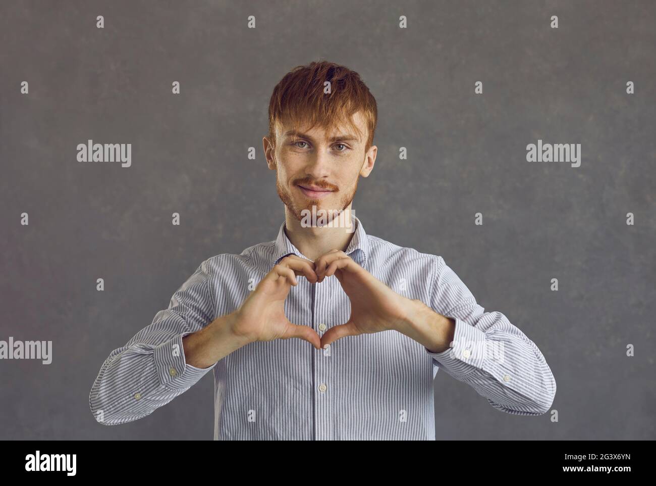 Caucasian red-haired man making heart gesture showing love and charity Stock Photo
