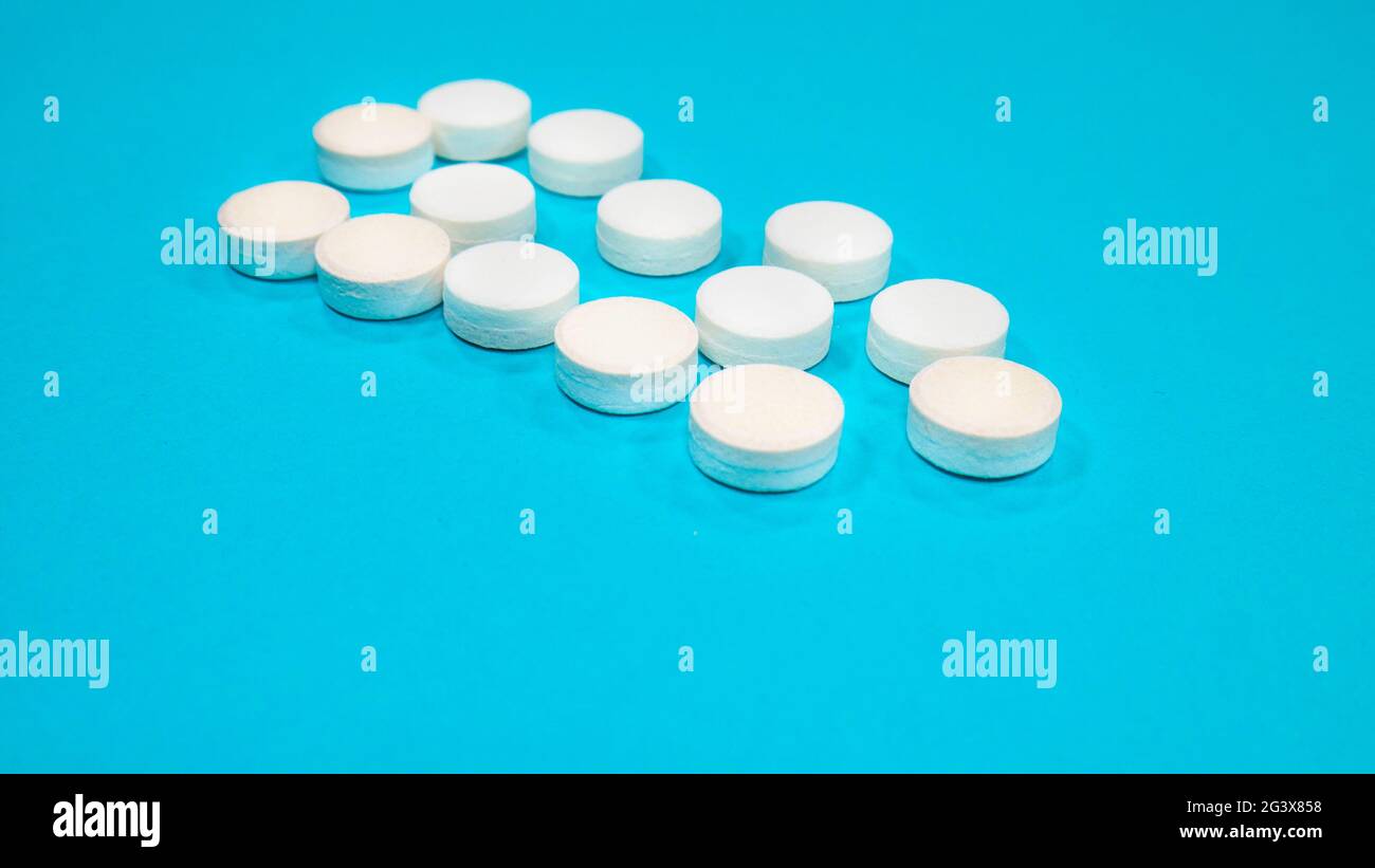 White medical pills on blue background. Stock Photo