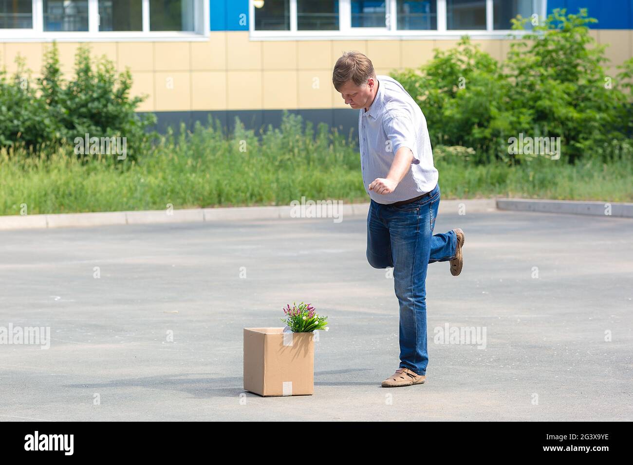Enraged man kicks a box of personal belongings after being fired. Stock Photo