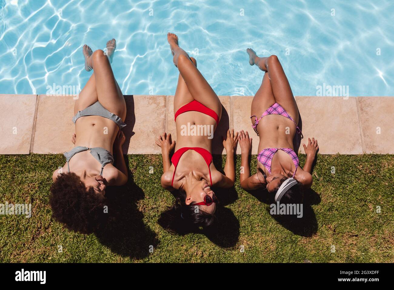 diverse-group-of-female-friends-sunbathing-by-pool-and-talking-stock