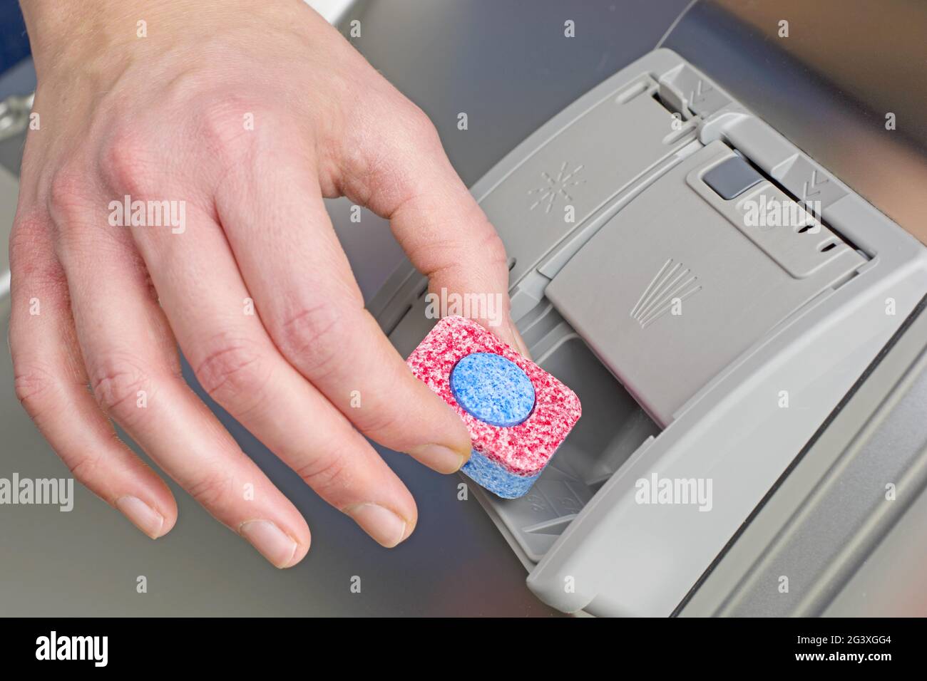 Loading the dishwasher with dishwashing tabs Stock Photo