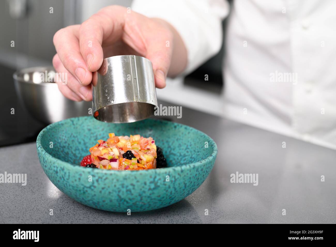 A chef prepares delicious vegetables tartare and finishes the preparation with a touch of class. Concept of: chef, kitchen, rest Stock Photo