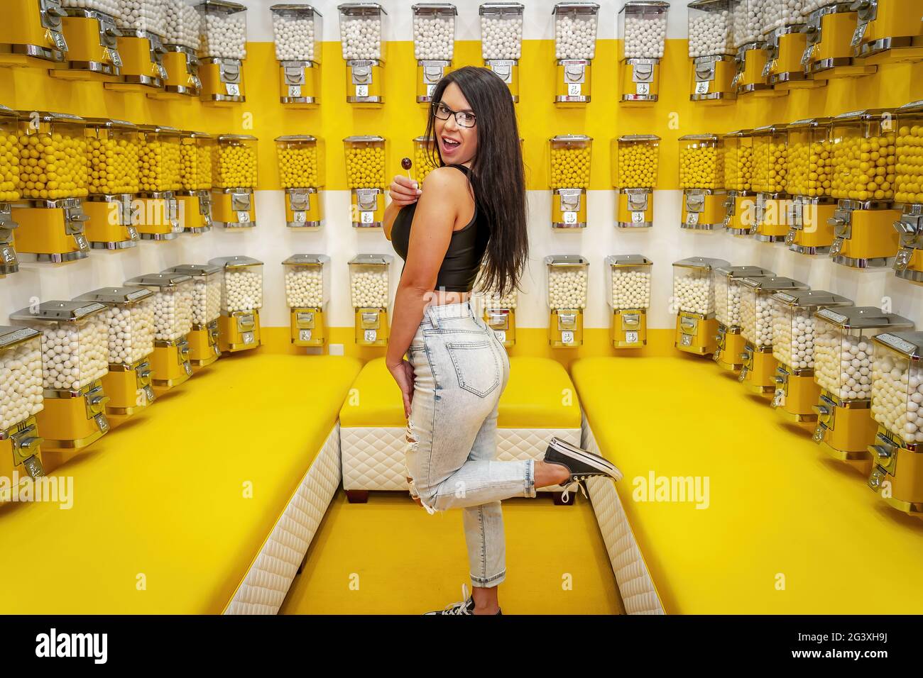 A Lovely Brunette Model Plays In A Room Full Of Gum Ball Machines Stock Photo