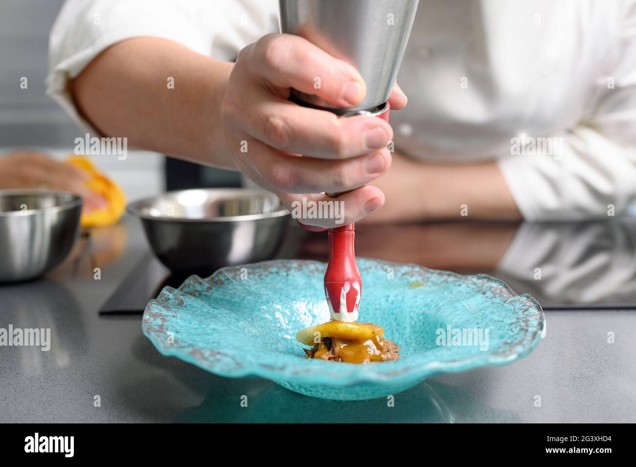 Professional chef holding a foam siphon in a restaurant kitchen. Stock Photo