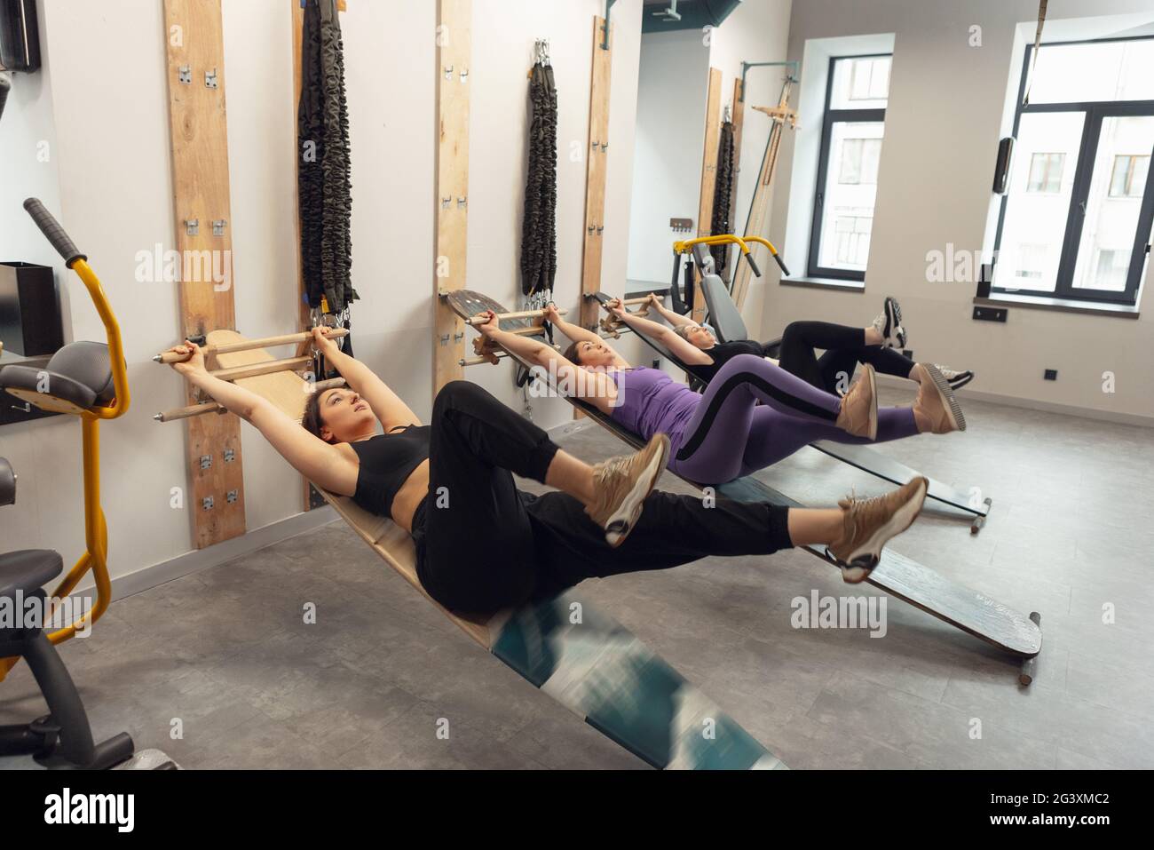 Athletic multinational people doing exercise with elastic rope in gym ...
