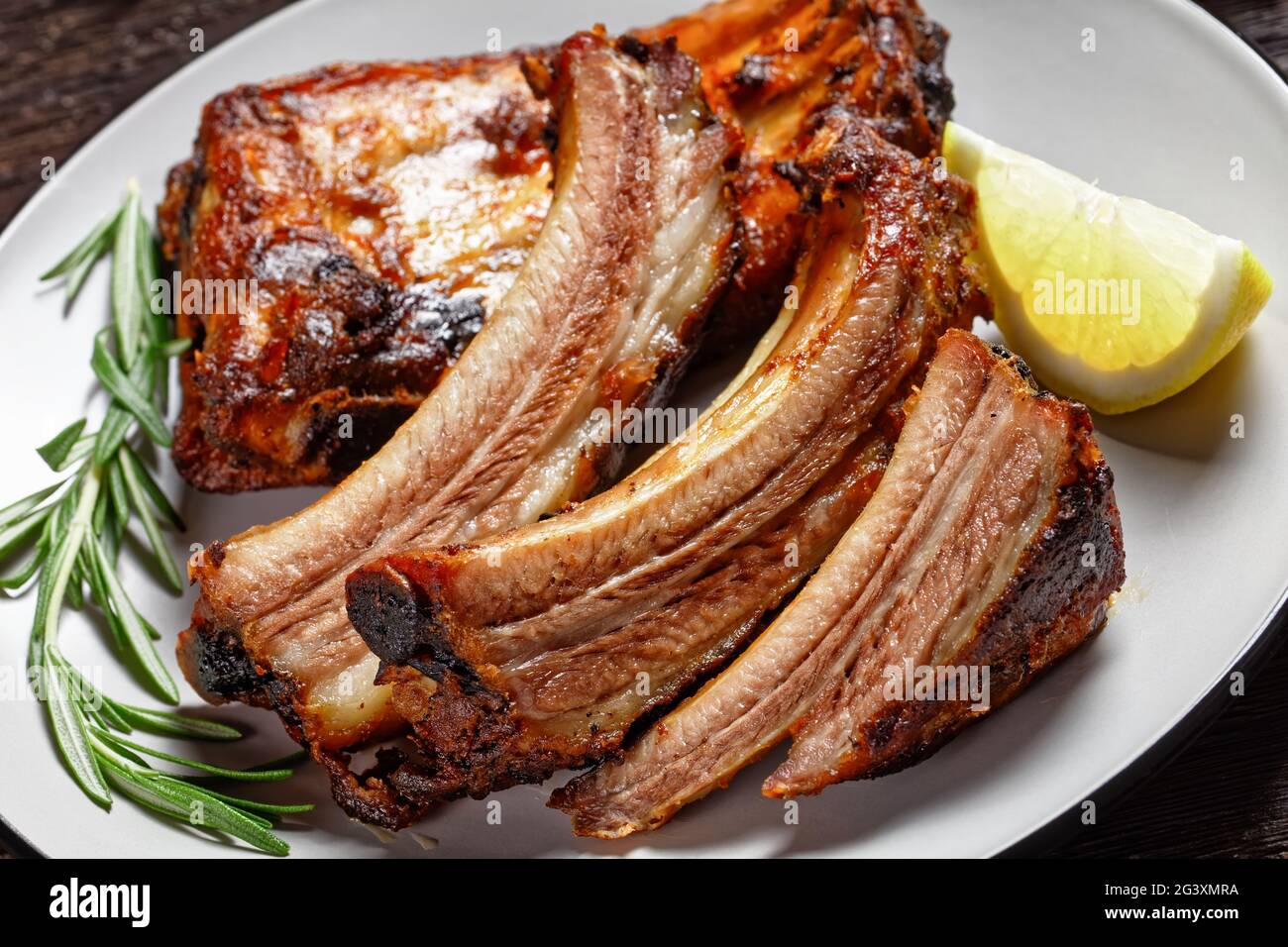 Hot Lemon Rib grilled pork ribs with lemon and rosemary on a plate on a dark wooden ...