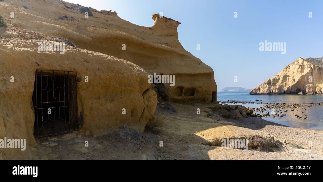 View of sandstone caves and dwellings at an idyllic cove and beach on the coast o Murcia Stock Photo