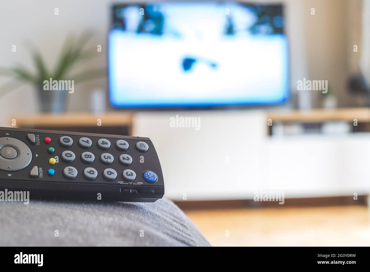 Remote control on the sofa, streaming on a smart TV. Stock Photo