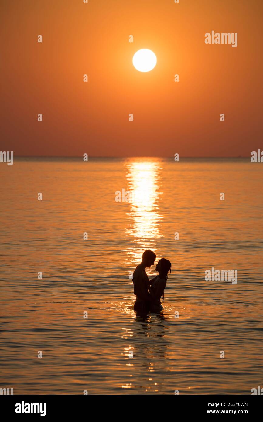 Silhouette of a romantic young couple in the water in front of Ong Lang