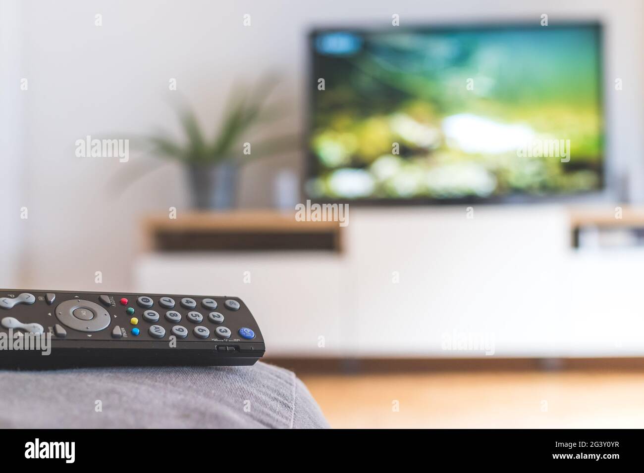 Remote control on the sofa, streaming on a smart TV. Stock Photo