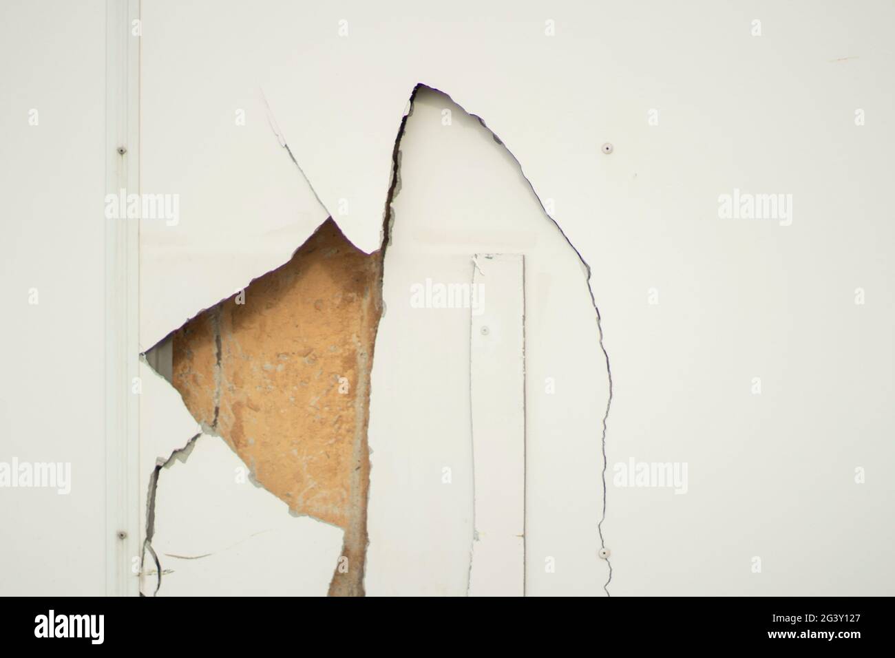 Hole in the wall. Broken surface. Cracked wall panel. A hole punched in