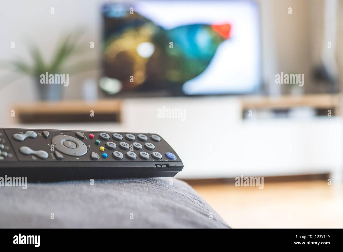 Remote control on the sofa, streaming on a smart TV. Stock Photo