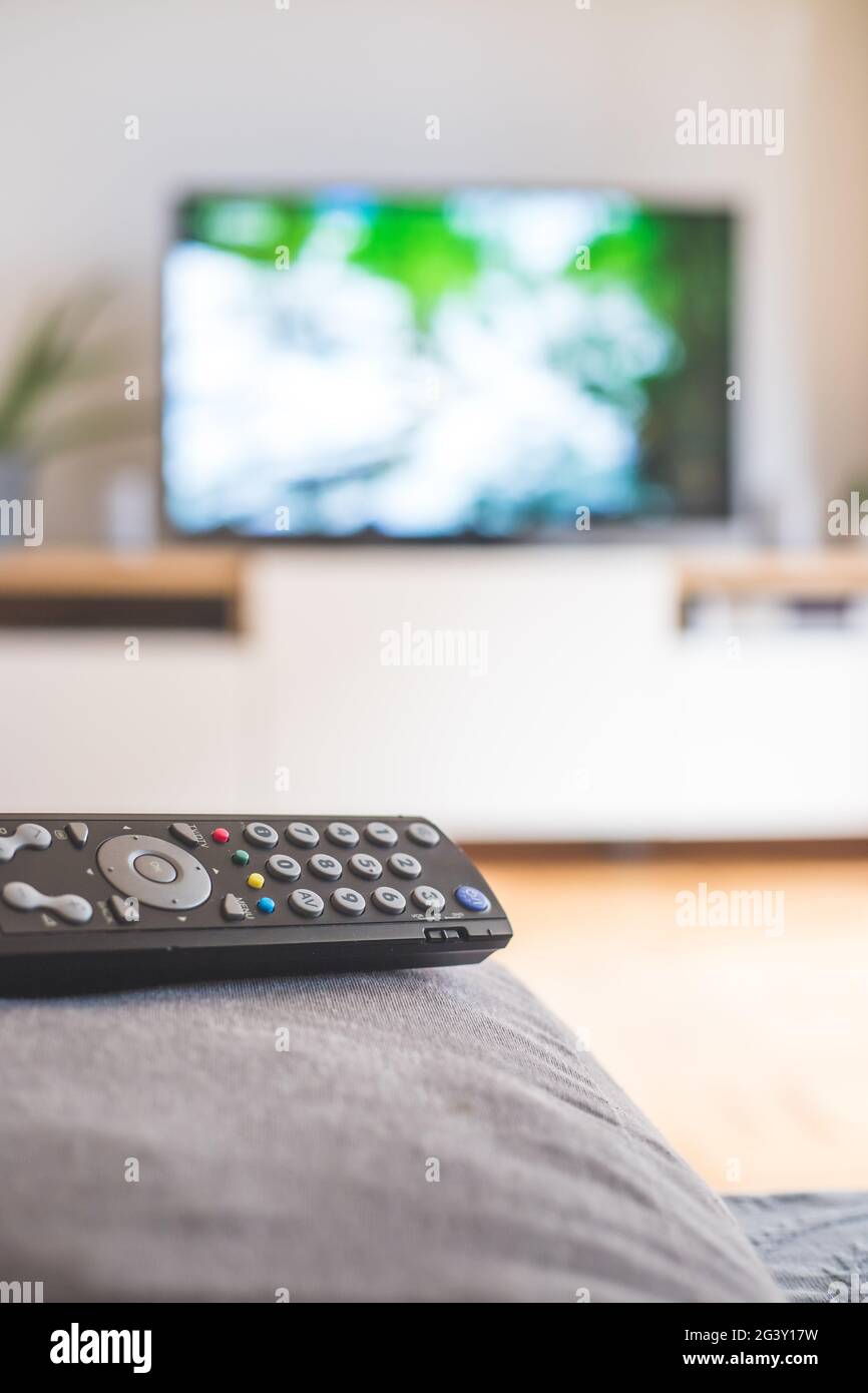 Remote control on the sofa, streaming on a smart TV. Stock Photo