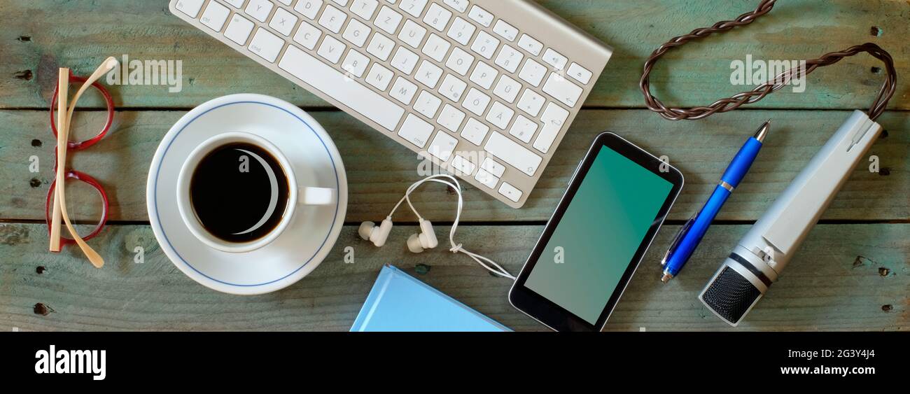 Recording podcast or audiobook concept, flat lay with smartphone, vintage microphone, coffee and keyboard on wooden table,panoramic Stock Photo