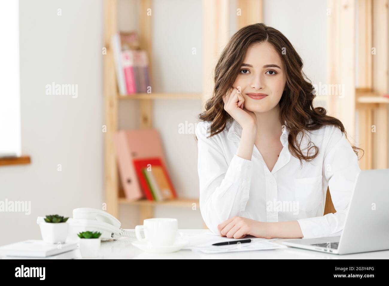 Young attractive woman at a modern office desk, working with laptop and ...