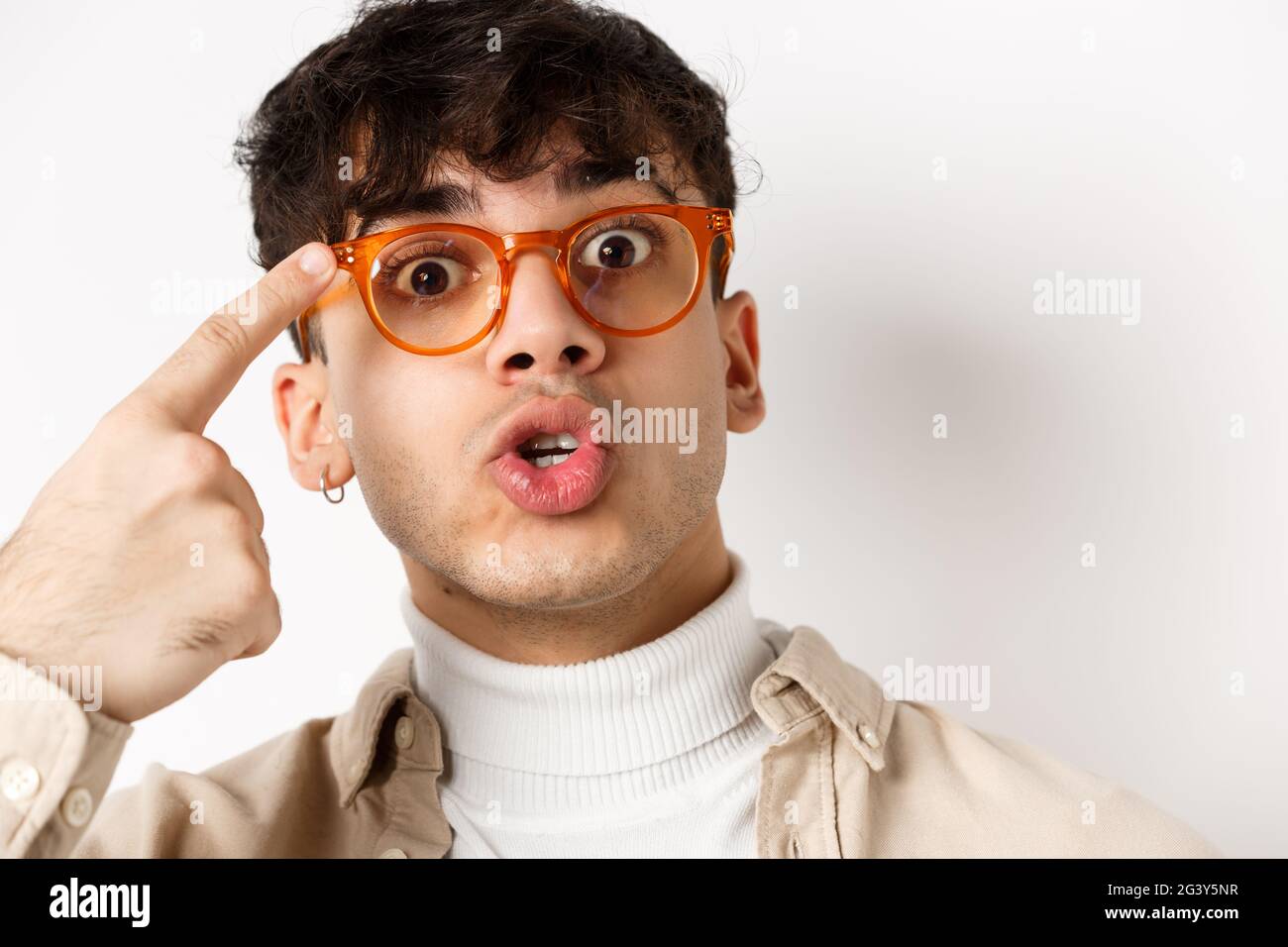 Close-up of cute and funny guy in glasses pointing at eyewear frames, recommending optic store, standing on white background Stock Photo