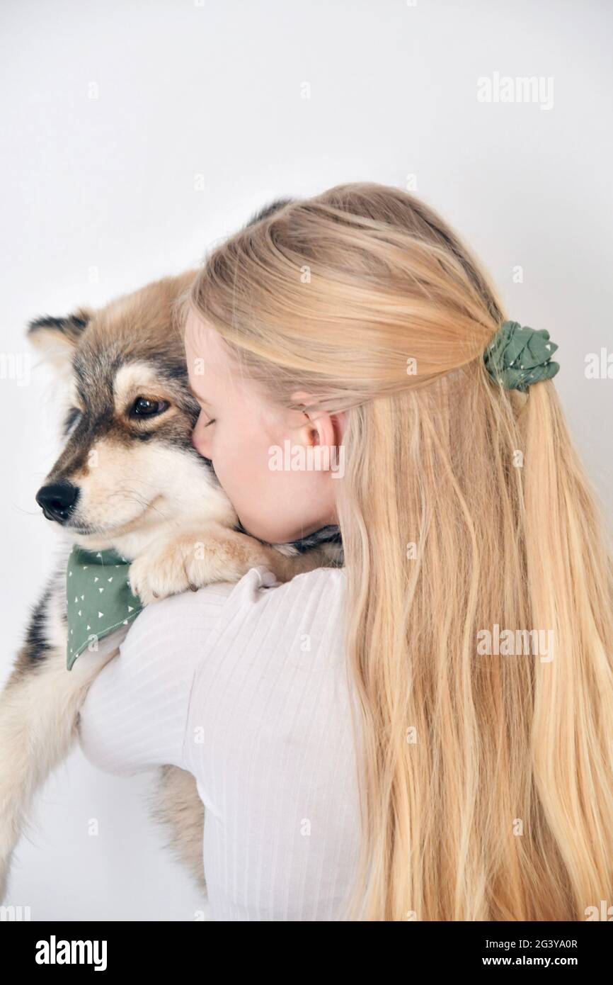 Photo of a young woman kissing a puppy Finnish Lapphund dog and wearing matching bandana and scrunchie Stock Photo
