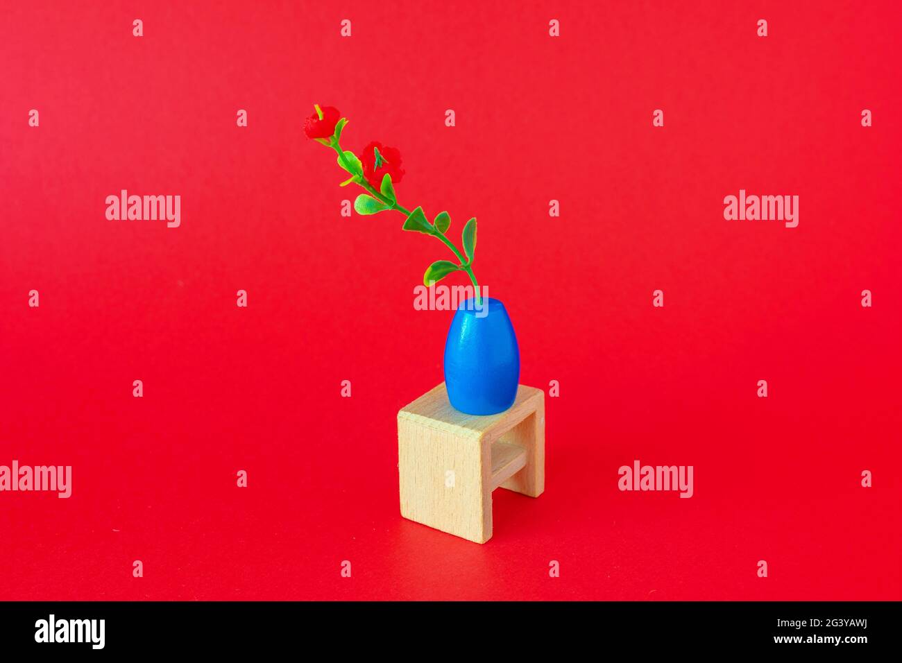 Toy flower on wooden chair on reg background Stock Photo