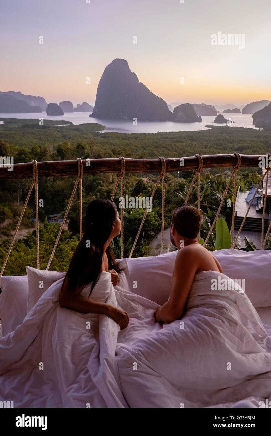 Couple man and woman mid age on vacation in Thailand waking up in the jungle with bedroom outside watching sunrise over the ocea Stock Photo