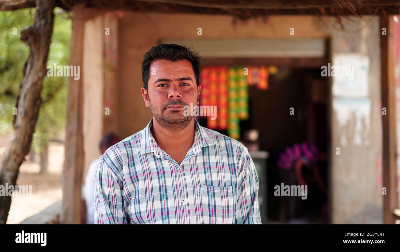 Portrait of charming young Indian man looking at camera while standing against blurred store background Stock Photo