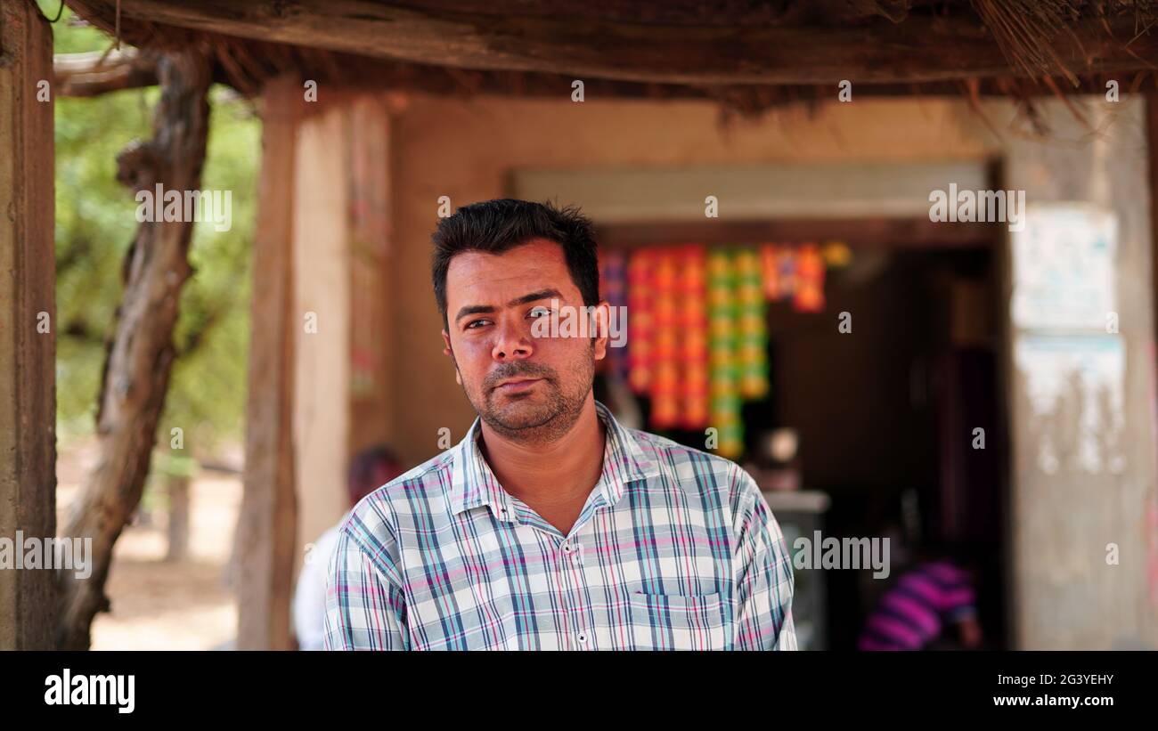 Portrait of charming young Indian man looking at camera while standing against blurred store background Stock Photo
