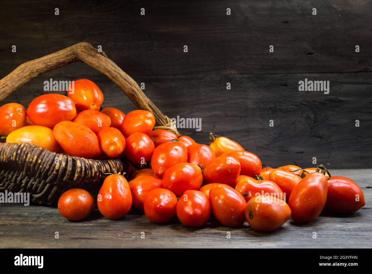 Basket overflowing with pear tomatoes on rustic wood Stock Photo