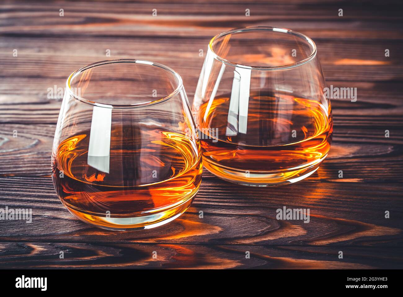 Two glass of whiskey, cognac, brandy on a dark brown wooden table. Bourbon. Strong alcohol drink close-up. Rum, scotch. Still life in a rustic style Stock Photo
