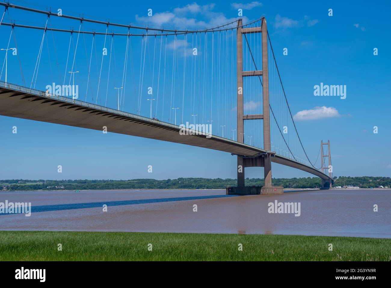 View of the Humber suspension bridge and river with blue sky on a bright sunny day. Stock Photo