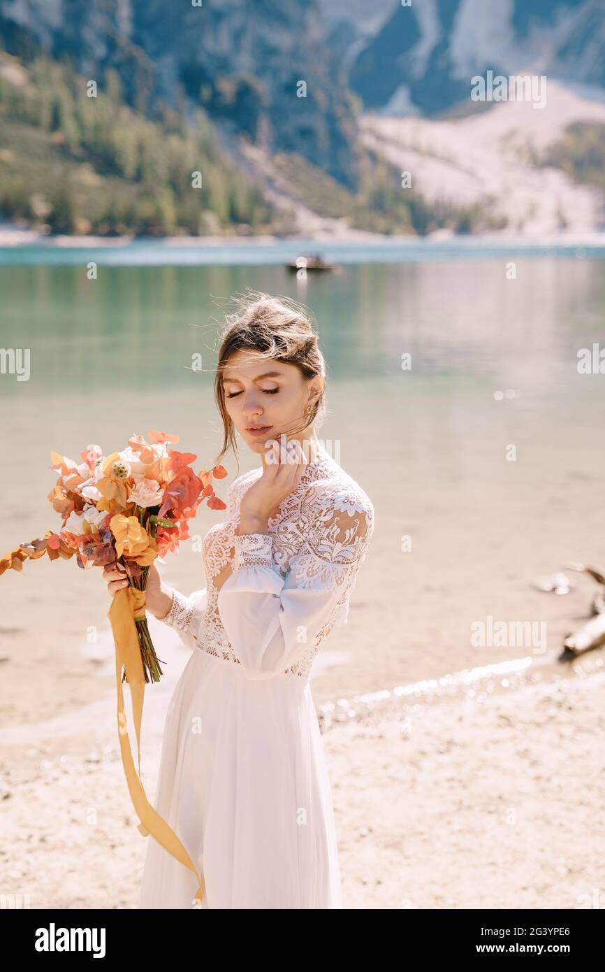 Beautiful bride in a white dress with sleeves and lace, with a yellow autumn bouquet of dried flowers and peony roses, on the La Stock Photo