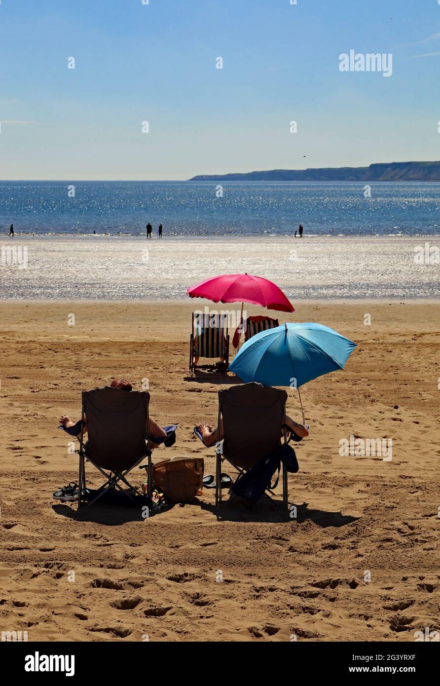 sun-bathers-on-scarborough-beach-using-red-and-blue-umbrellas-to-shade