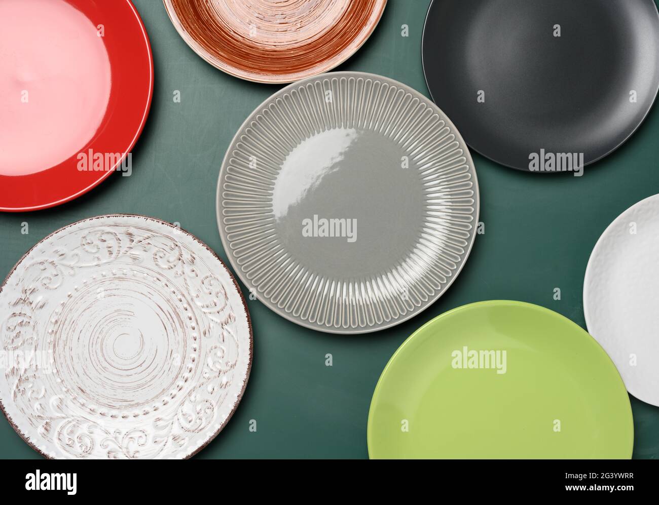 Empty round multicolored ceramic plates on green background Stock Photo