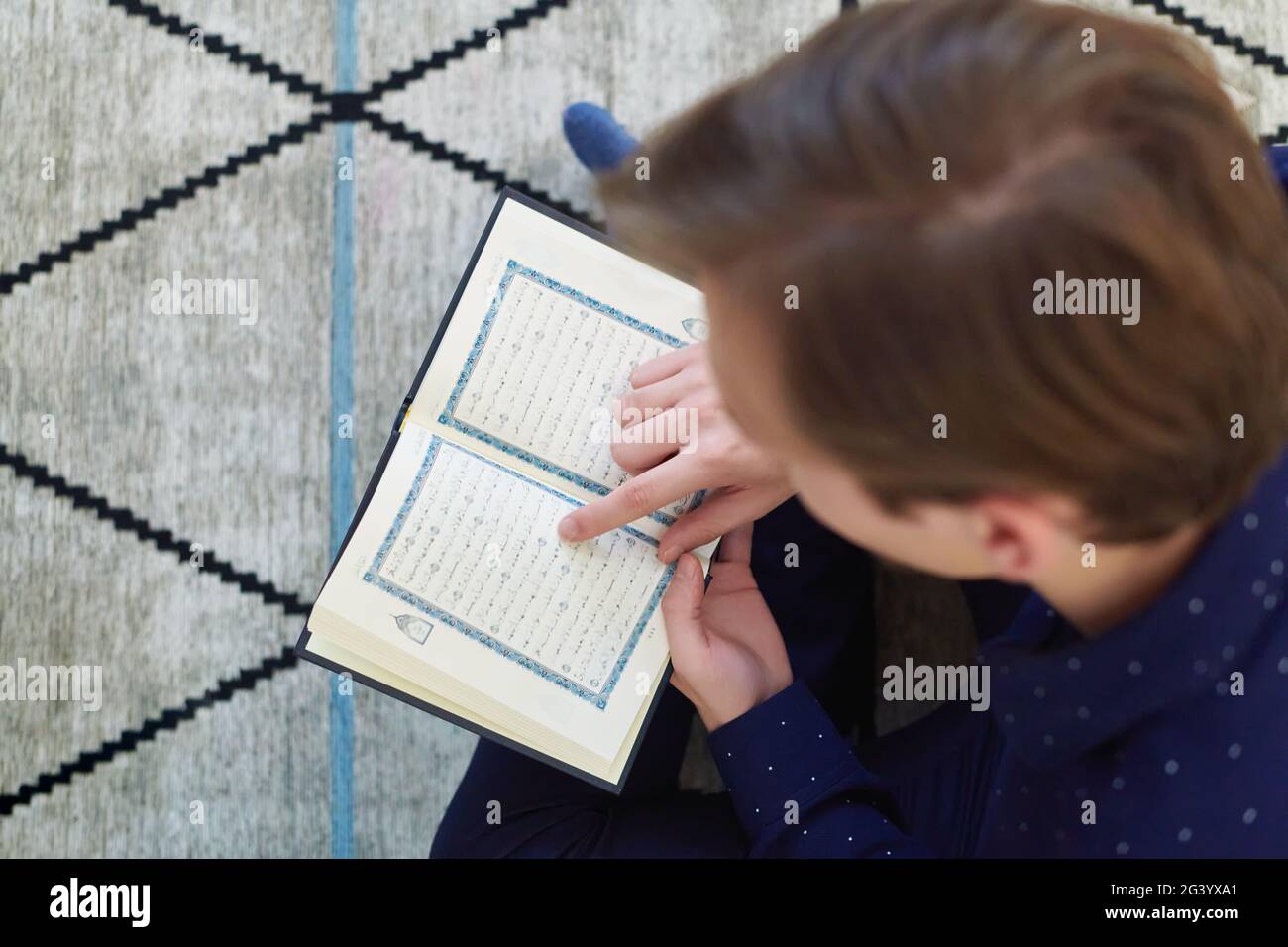 Young muslim man reading Quran during Ramadan Stock Photo