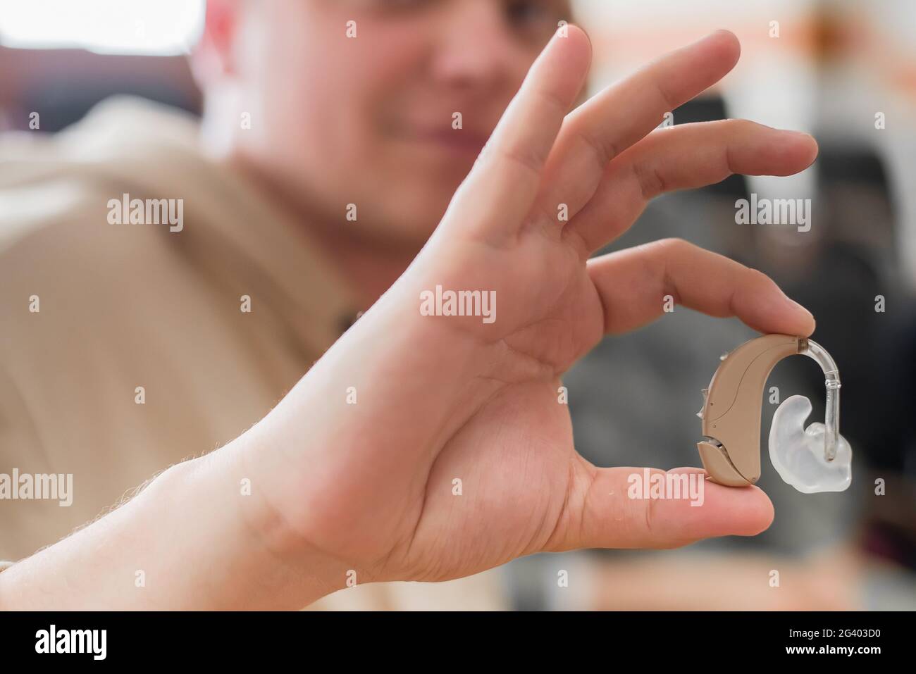 A young man puts on a hearing aid. Portable sound amplifier for the