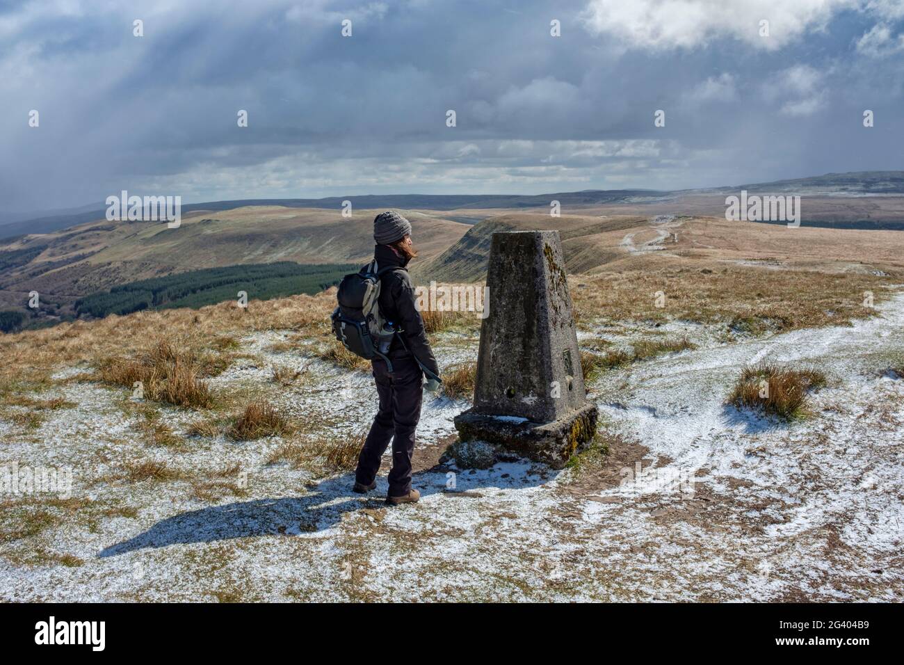 Woman at a mountain top trig point in the Brecon beacons national park. Stock Photo