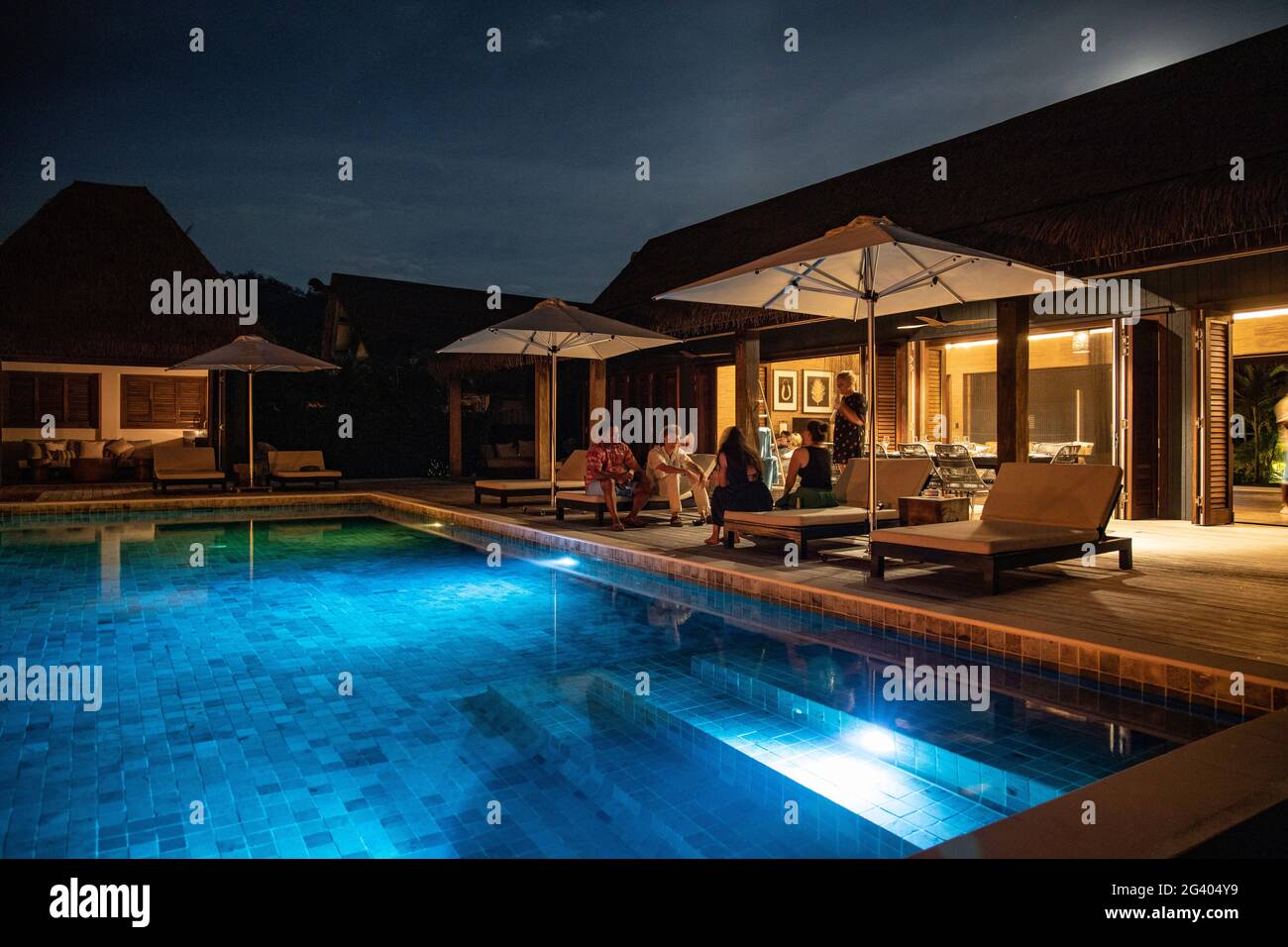 People relaxing by the private swimming pool of a residence villa accommodation at Six Senses Fiji Resort at night, Malolo Island, Mamanuca Group, Fij Stock Photo