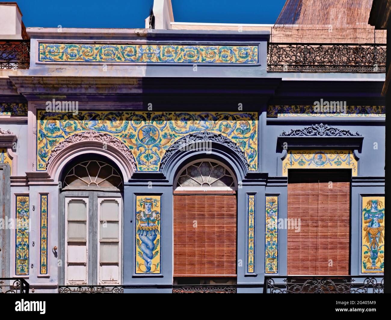 Frontal Art Nouveau facade, richly decorated with painted tiles, in Santa Cruz de Tenerife. The doors have round arches and glass decorations, the til Stock Photo