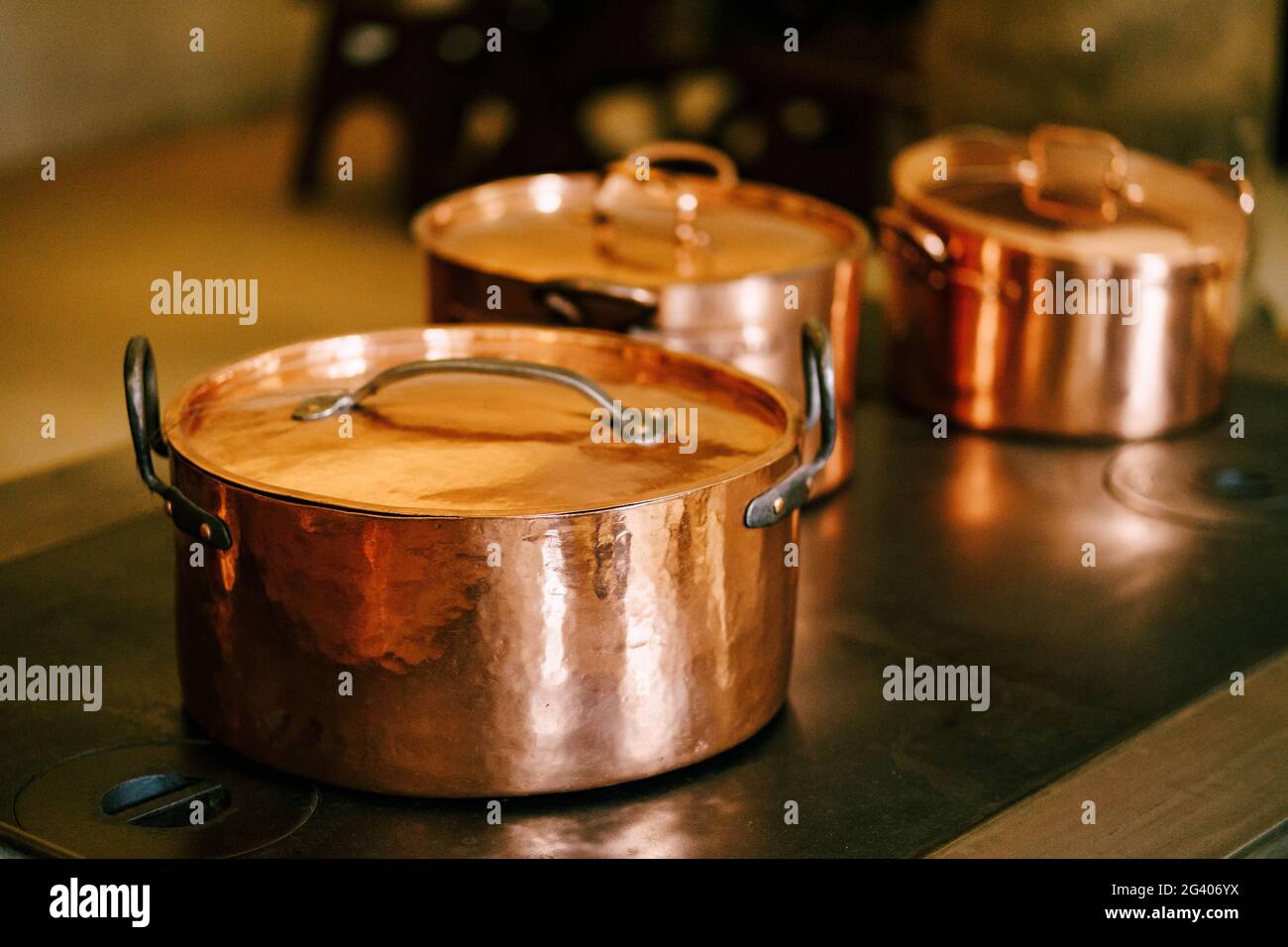 Closeup of copper pots with closed lids on an antique burner stove