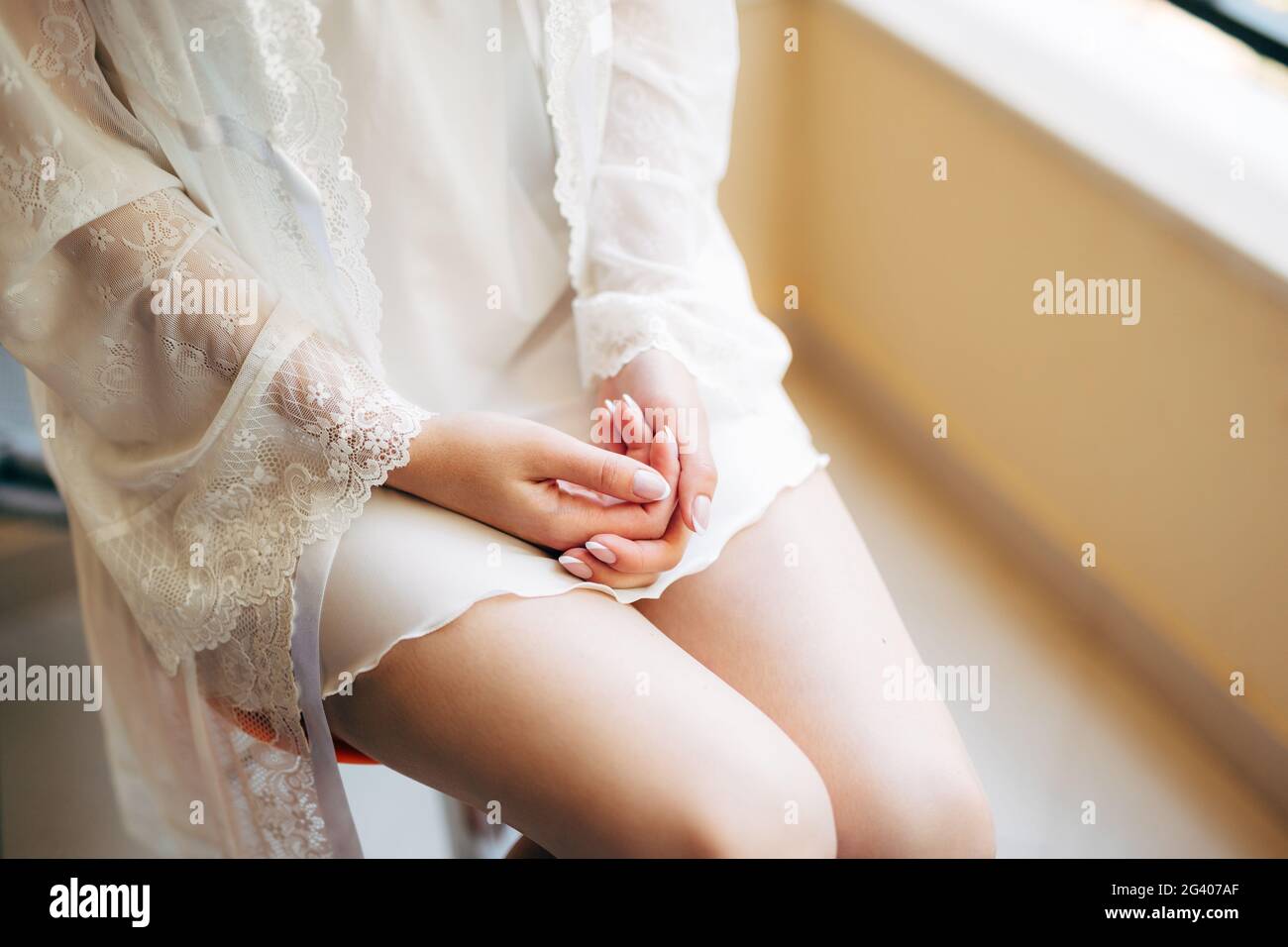 Young girl in peignoir put her hands on her knees Stock Photo