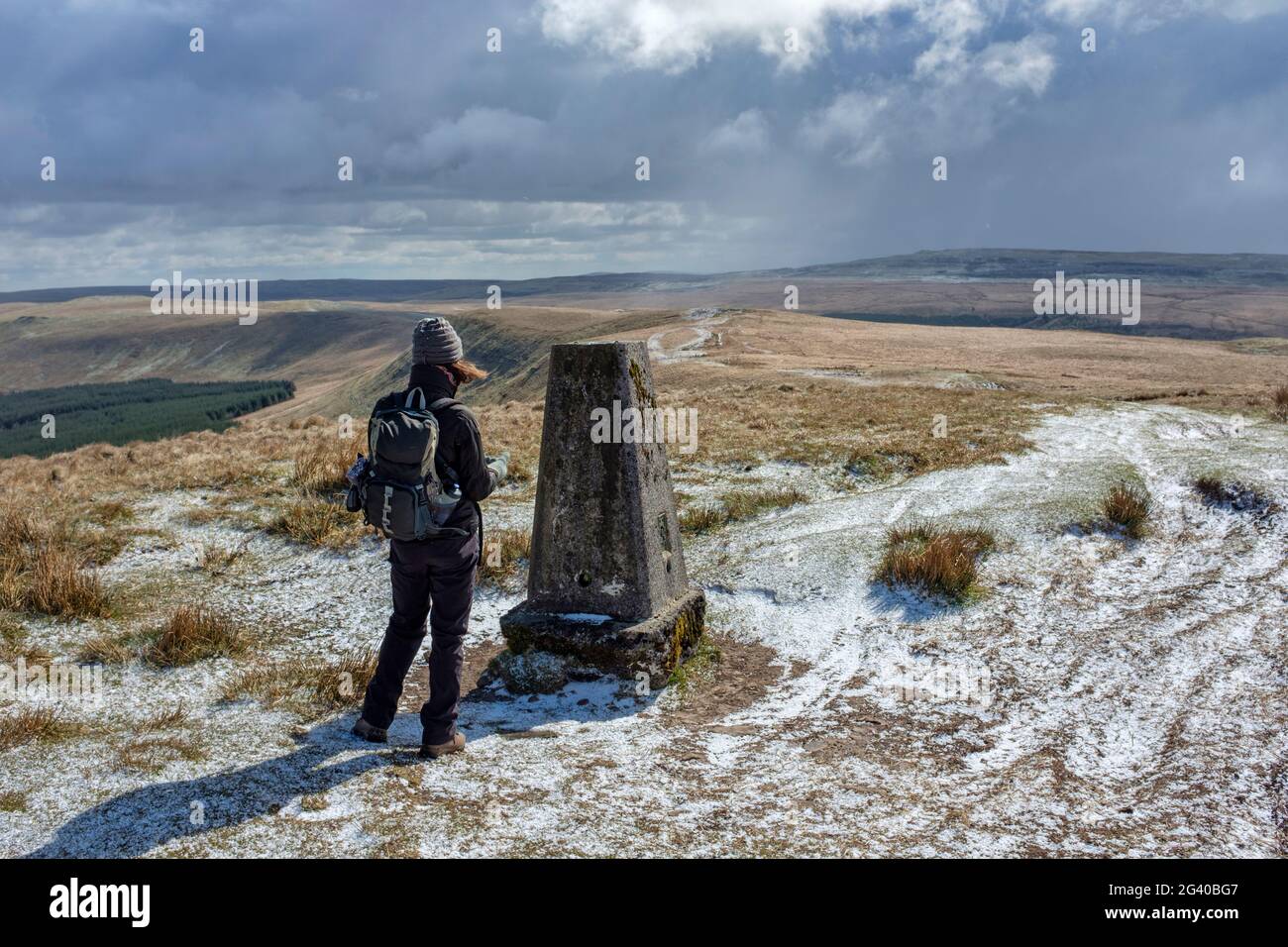 Woman at a mountain top trig point in the Brecon beacons national park. Stock Photo