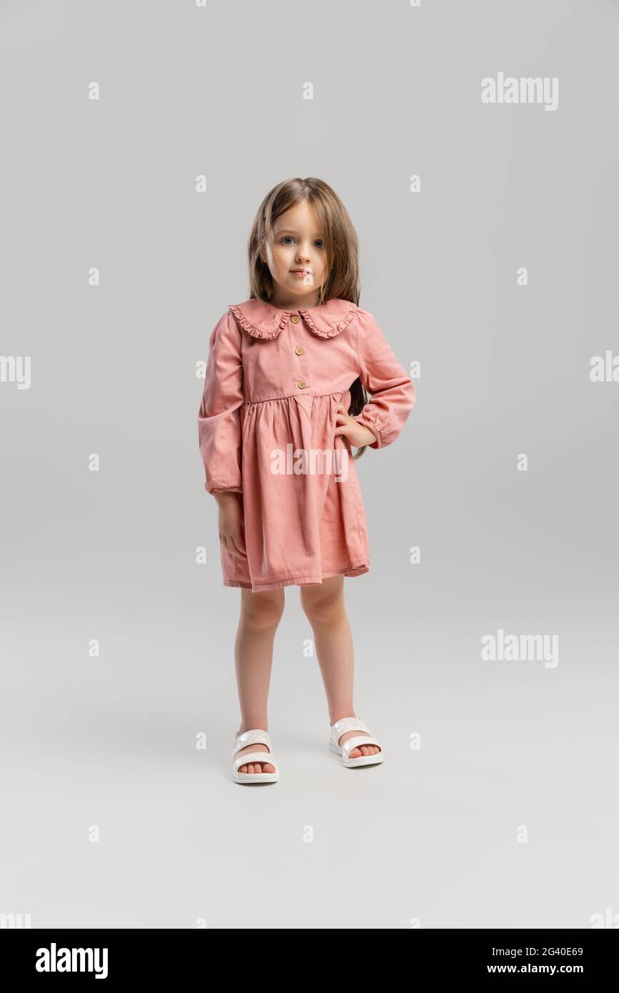 Portrait of little Caucasian cute girl posing isolated over gray studio ...