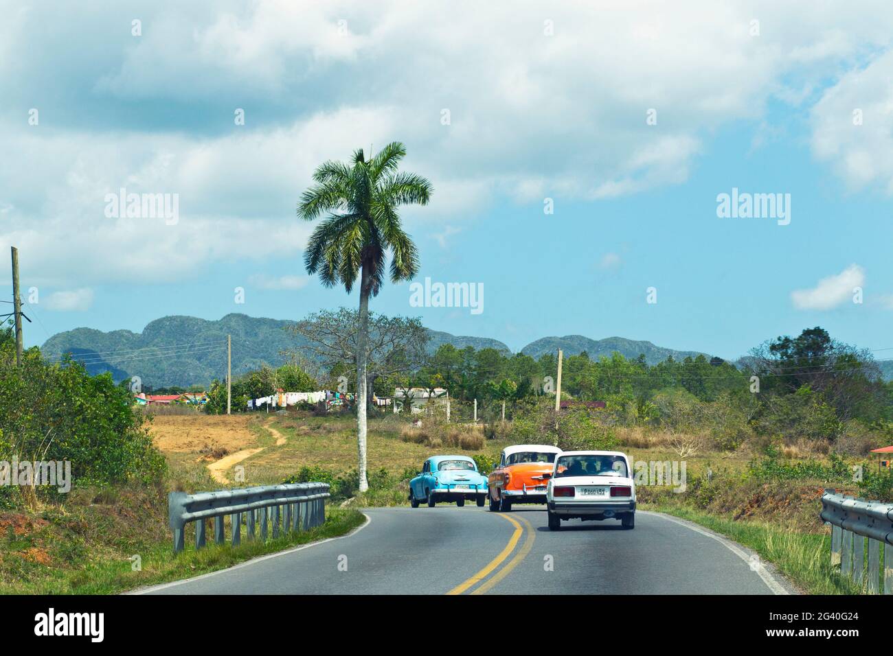 Classic cars driving through the Viñales Valley in Cuba Stock Photo