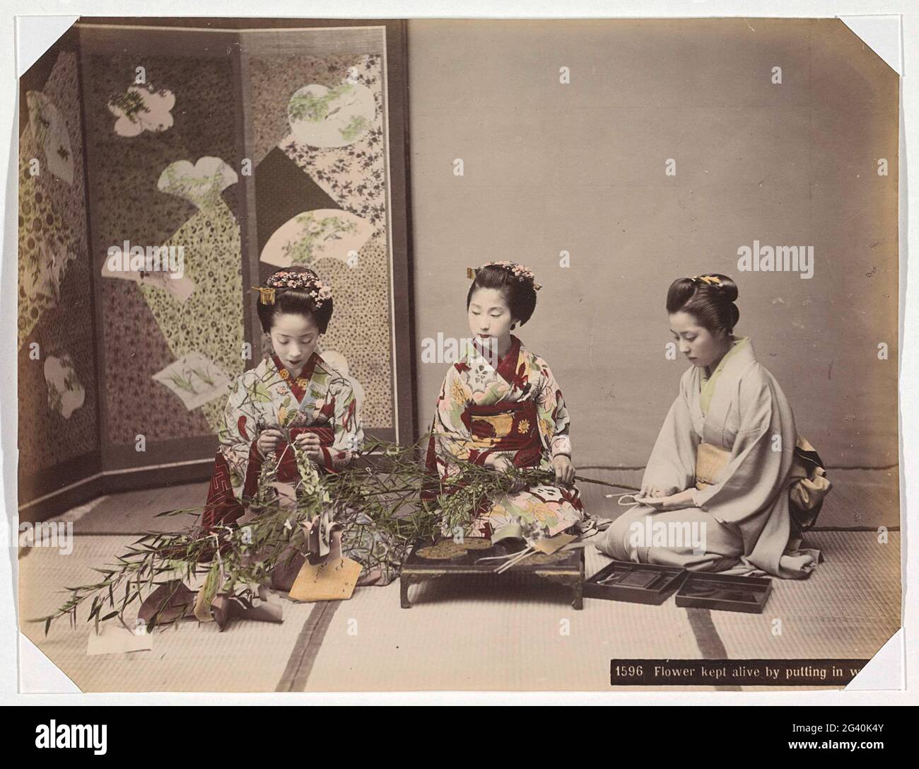 Three Japanese women arrange flowers; Flower Kept Alive by putting in