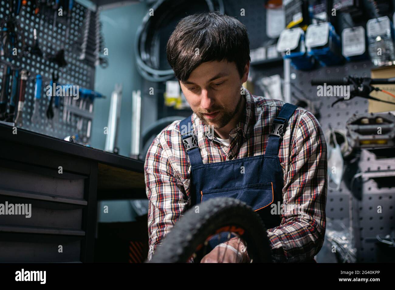 Bike shop mechanic fixing bicycle wheel in workshop. Serviceman repair, maintenance cycle. Velocipede repairing bicycle in bike Stock Photo