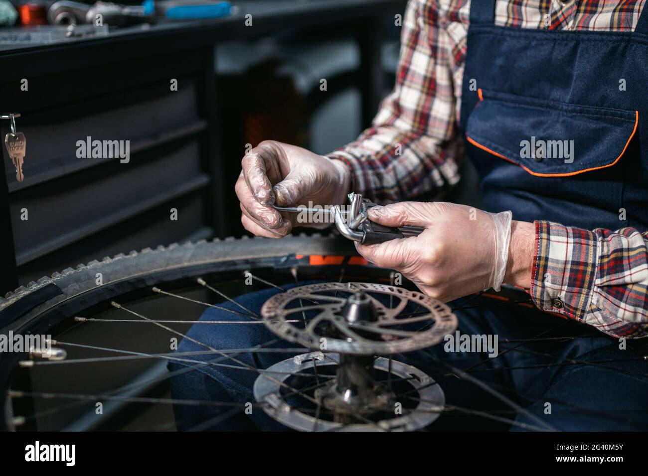 Bicycle mechanic fixing cycle wheel in repair shop. Velocipede service. Repairer male bike shop engineer fix bicycle wheel in wo Stock Photo