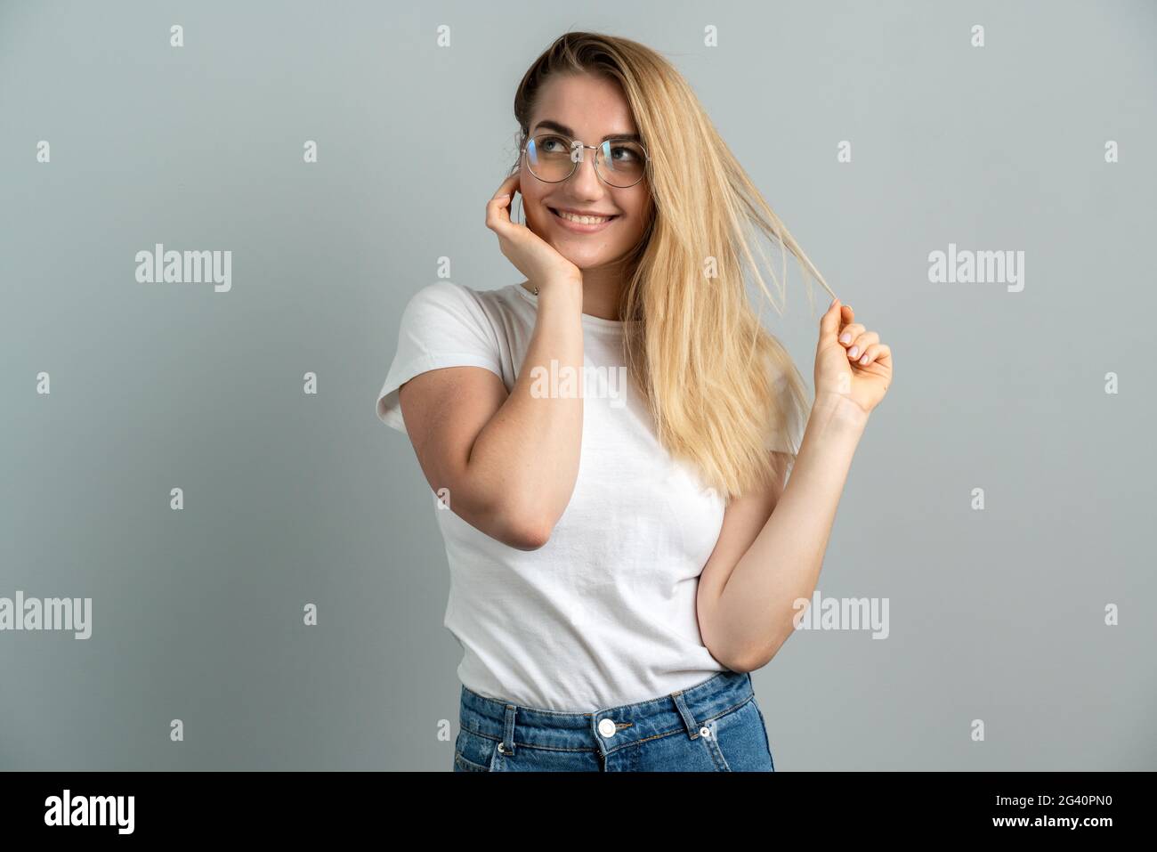 Portrait of dreamy pretty lovely young lady wear glasses isolated on grey color background. The girl is playfully posing Stock Photo