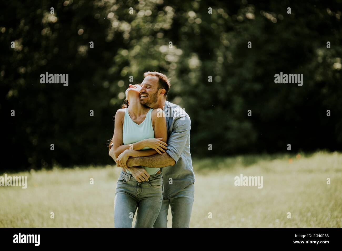Affectionate young couple having fun on the green grass at the park ...