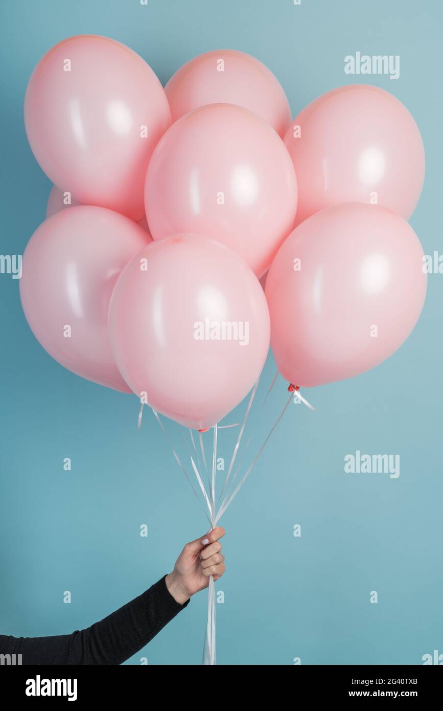 Pink air flying balloons in man hands isolated on blue background. Man in  shirt holding many pink air balloons, free space. Summer, holidays,  celebrat Stock Photo - Alamy