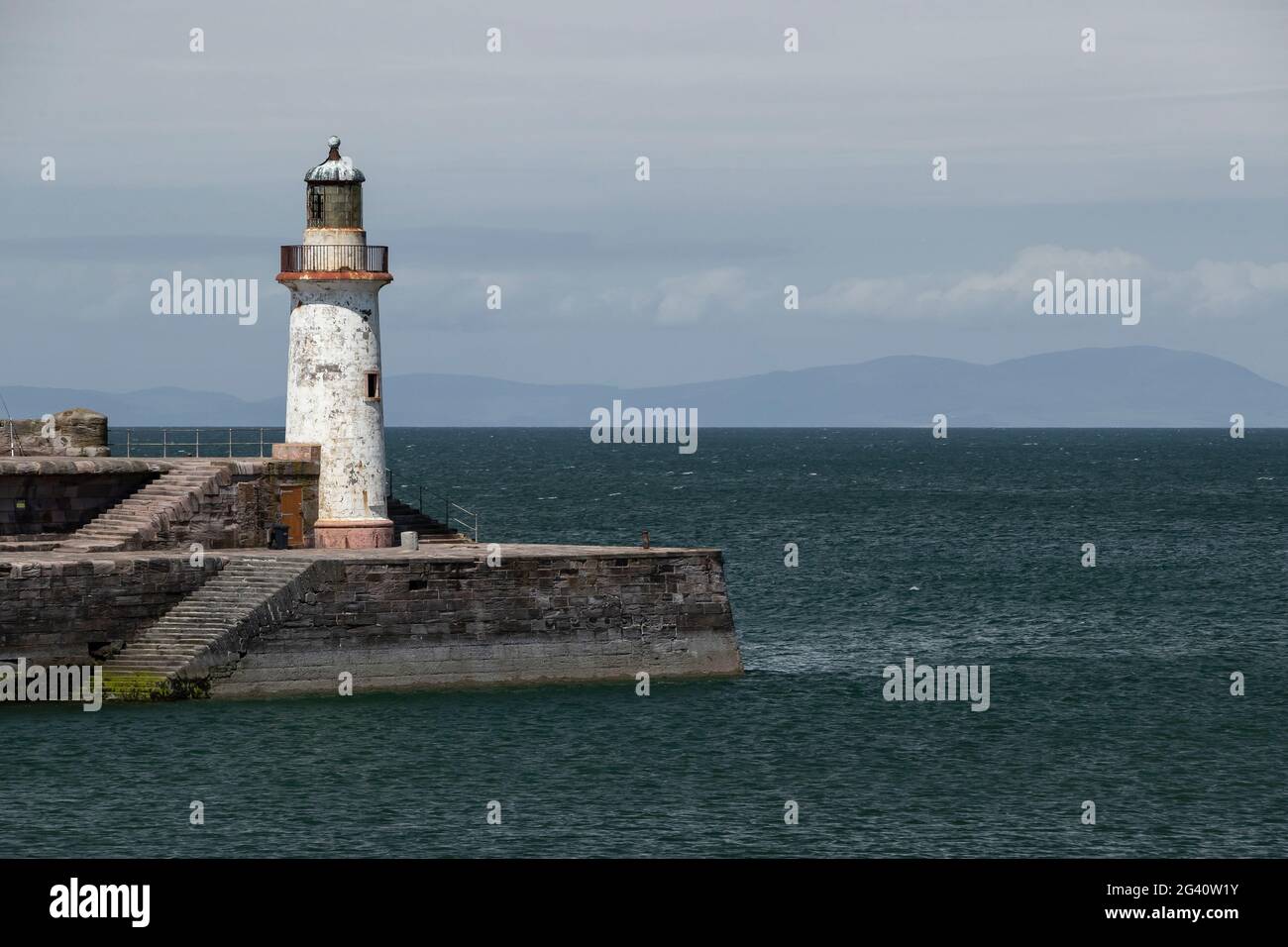 Whitehaven, Cumbria, England. 15 June 2021. Witehaven's west pier lighthouse showing part of Scotland on the horizon. Stock Photo